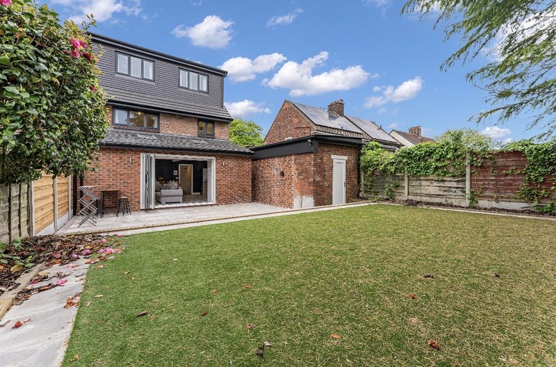 Brick house with modern extension, patio area, and large lawn garden