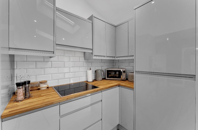 Modern kitchen with white cabinetry, wooden countertop, subway tile backsplash and appliances