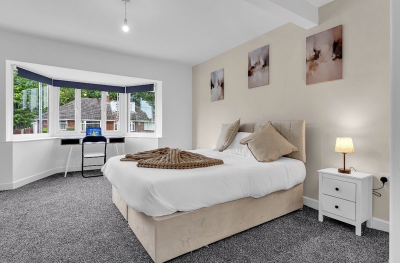 Bright bedroom with double bed, desk area, window seat and framed wall art