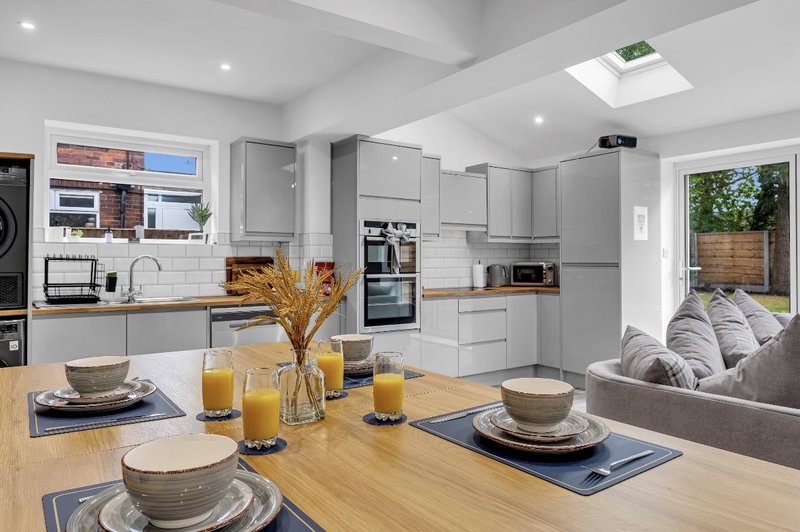 Modern open-plan kitchen and dining area with wooden island, grey cabinetry, and garden view
