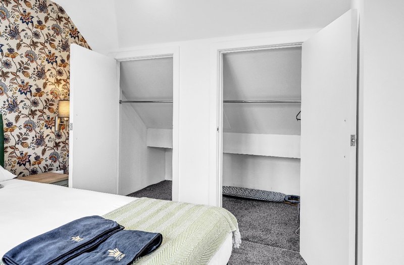 Bedroom with double bed, two open wardrobes and floral patterned wall feature