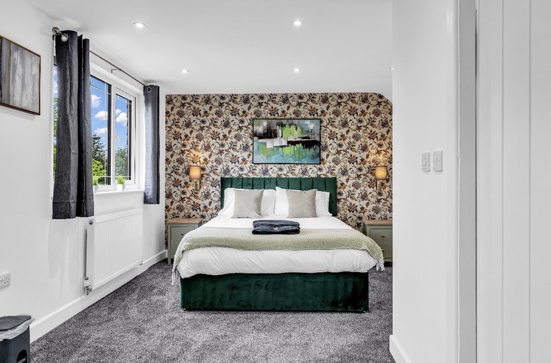 Modern bedroom with double bed, floral wallpaper accent wall, and wall-mounted TV