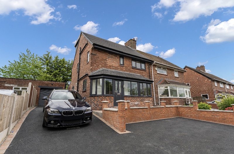 Brick semi-detached house with driveway, parked car, and front garden