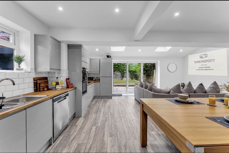 Modern open-plan kitchen and dining area with grey cabinetry, wooden island, and garden view