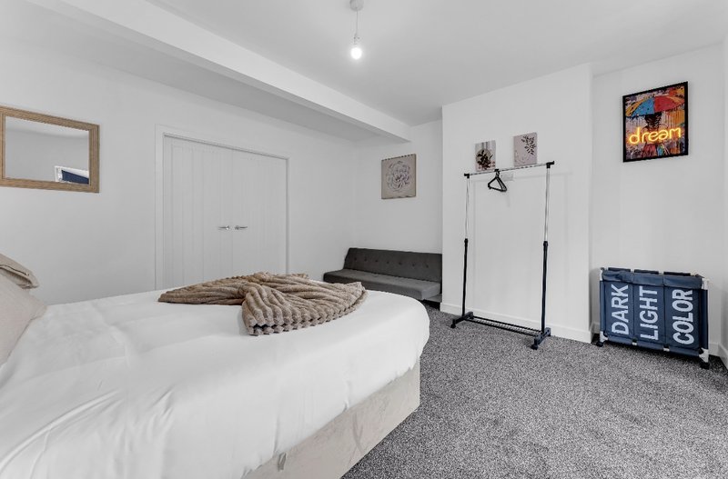 Modern bedroom with double bed, grey carpet, white walls and minimalist furnishings