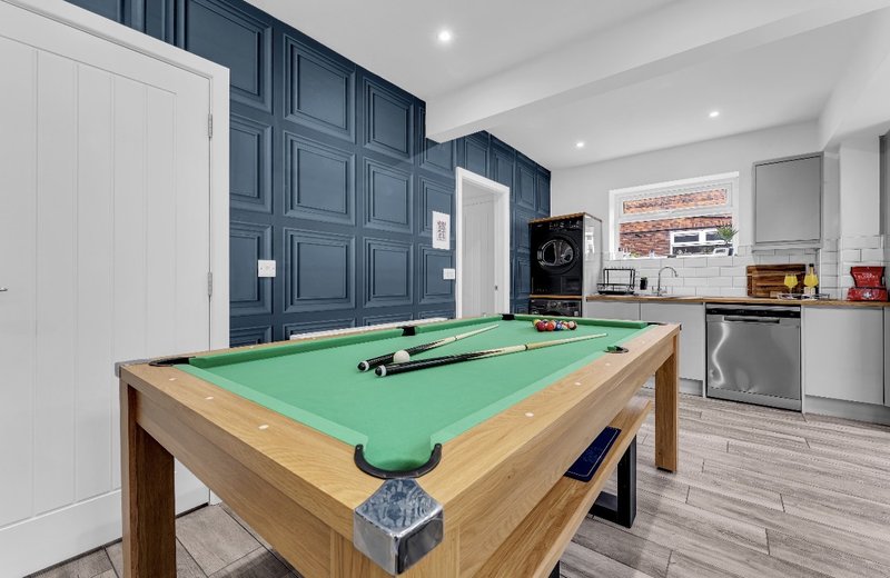 Games room with pool table, dark blue panelled walls, kitchen area and appliances