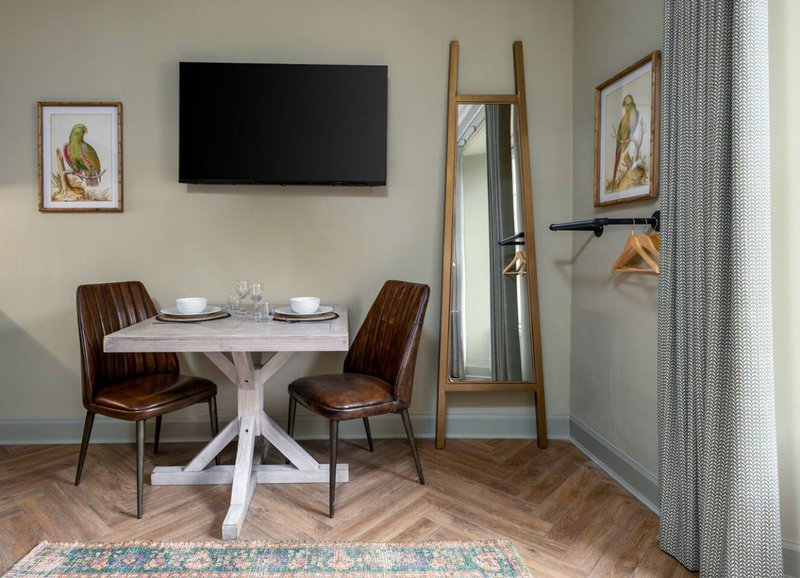 Dining area with white round table, brown chairs, wall-mounted TV, and decorative wall art