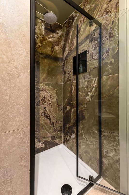Modern bathroom shower enclosure with dark marble-effect tiled walls and white tray