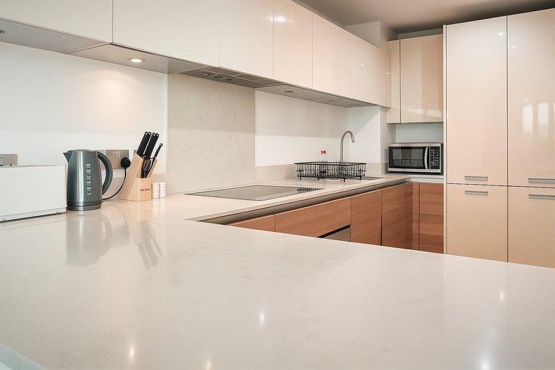 Modern kitchen with white countertop, two-tone cabinetry, stainless steel sink and appliances