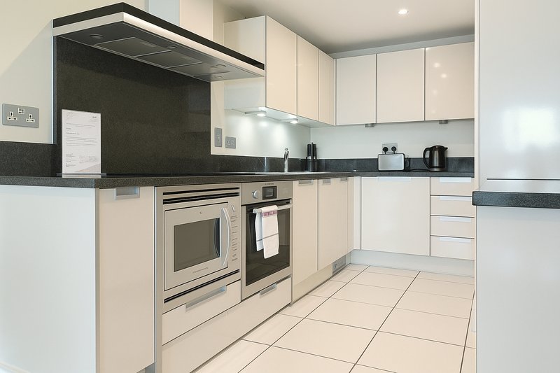 Modern kitchen with cream cabinets, black countertop, stainless steel appliances and tiled flooring