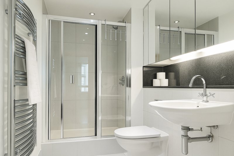 Modern bathroom with walk-in shower, white sink, toilet and heated towel rail