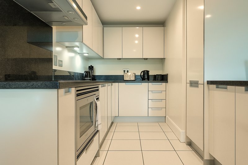 Modern kitchen with white cabinetry, dark worktop, stainless steel oven and tiled flooring