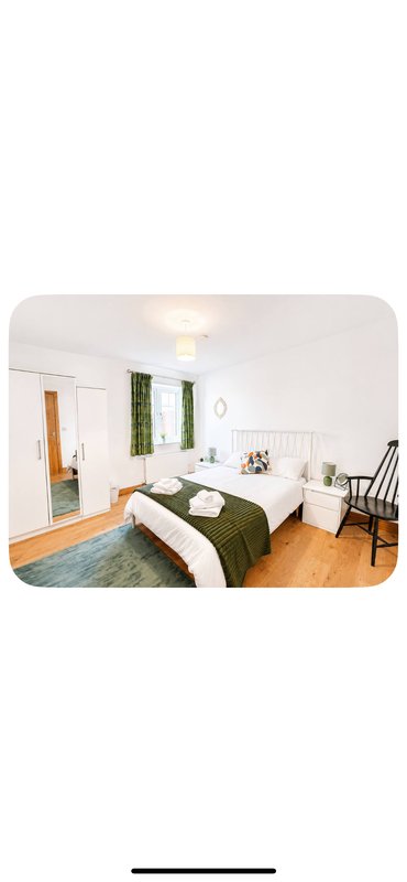 Bright bedroom with double bed, green bedding, wooden floor, and ensuite door