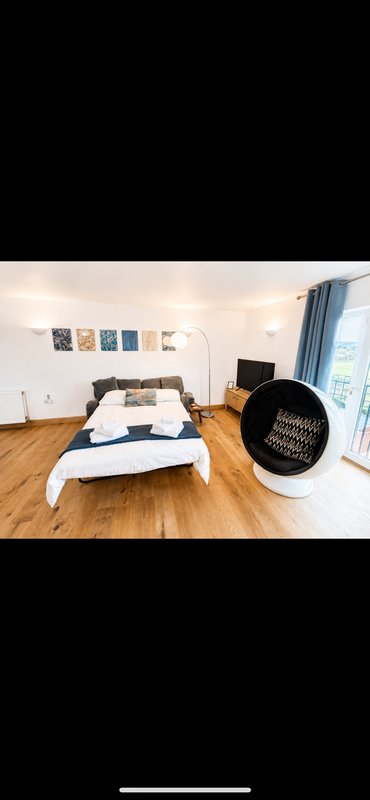 Bright bedroom with double bed, wooden floor, wall art, and modern furnishings