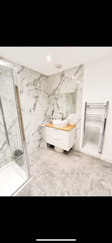 Modern bathroom with marble-effect wall panels, walk-in shower, vanity unit and heated towel rail