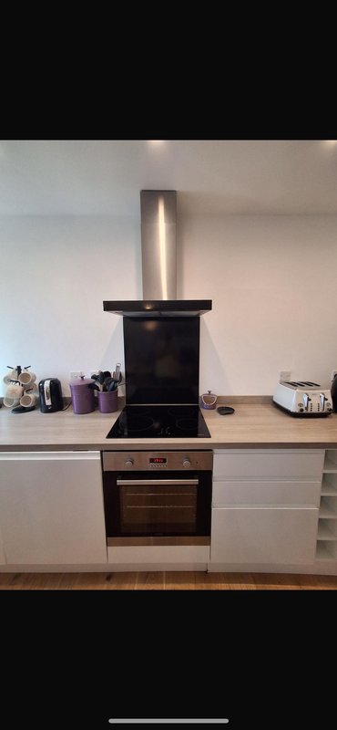 Modern kitchen with built-in oven, extractor hood, white cabinetry and countertop