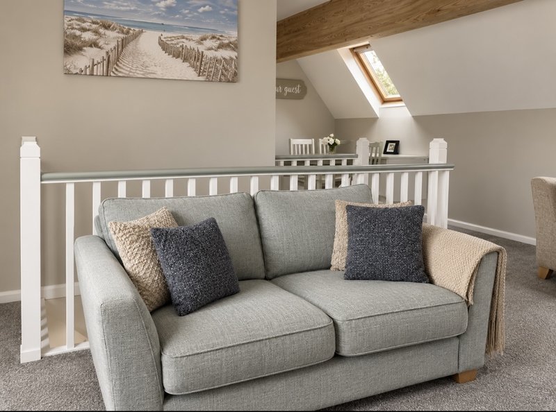 Bright attic room with grey sofa, white crib, skylights and beach-themed wall art