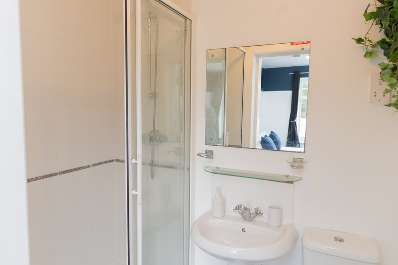 Clean bathroom with shower enclosure, round sink, mirror and cream walls