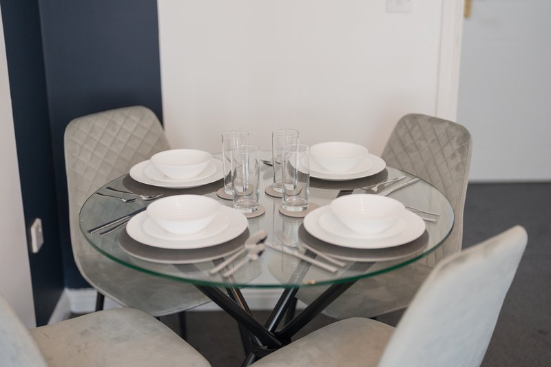 Modern dining table set for four with white plates, glasses and place settings