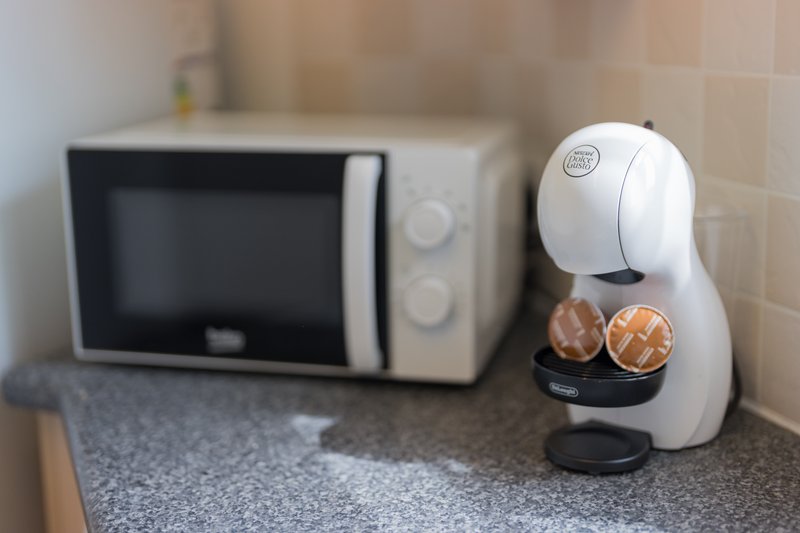 Kitchen counter with microwave and coffee machine with capsules