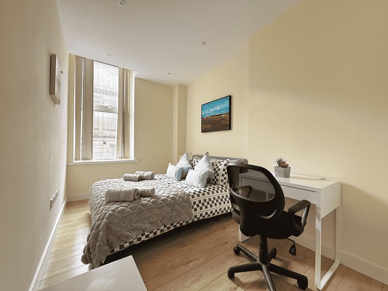 Bright bedroom with single bed, desk, chair, window and wooden flooring