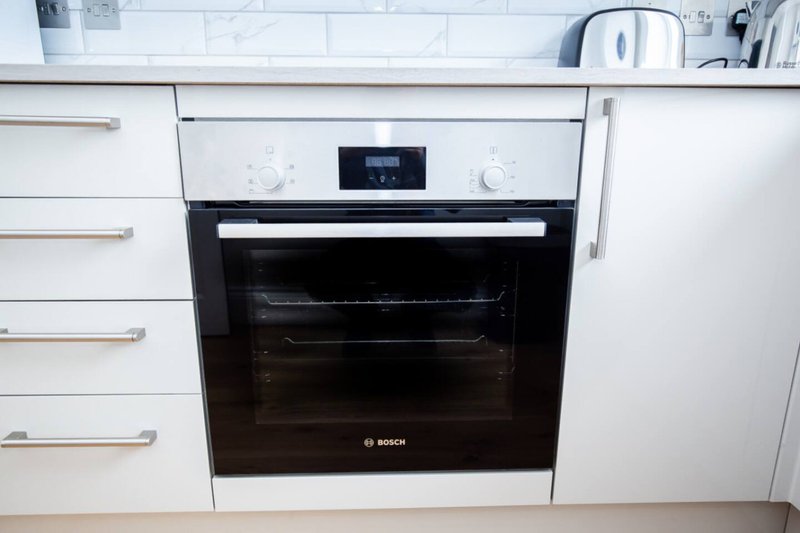 Modern kitchen with white cabinetry, built-in Bosch oven, and stainless steel appliances