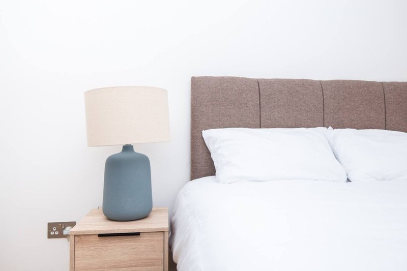 Bedroom with double bed, upholstered headboard, bedside table and lamp