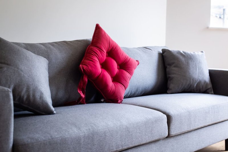 Gray upholstered sofa with gray and pink cushions in bright living room