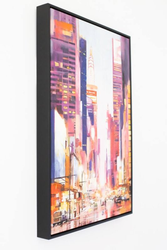 Framed cityscape artwork showing colorful urban buildings and street scene at dusk