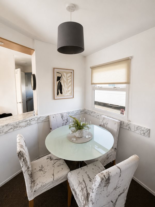 Bright dining nook with round white table, marble-patterned chairs, pendant light and window