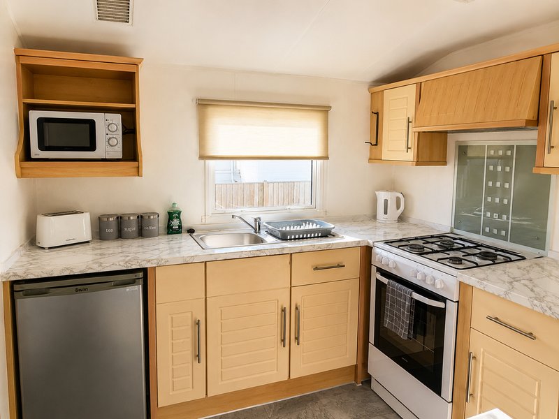 Modern kitchen with light wood cabinets, marble countertop, gas range and dishwasher