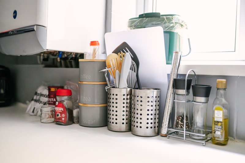 Kitchen countertop with organized storage containers, utensils, and food items near window