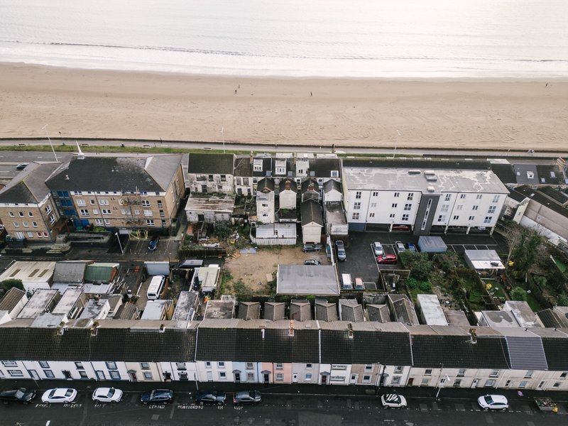 Aerial view of beachfront residential buildings and seafront promenade with parking