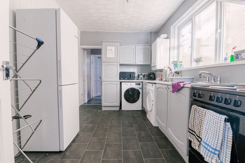 Kitchen with white cabinets, washing machine, gas range, and large fridge freezer