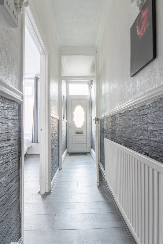 Long bright hallway with grey brick-effect wall panels, white radiator and tiled flooring