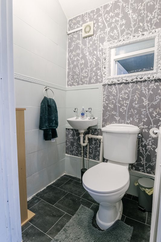 Bathroom with toilet, pedestal sink, patterned wallpaper and small window