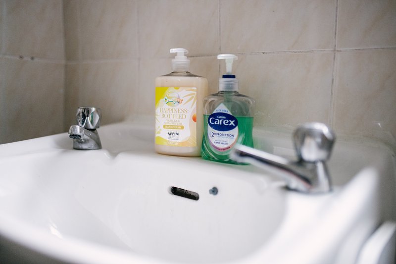 Bathroom sink with soap dispenser, hand sanitizer, and toiletries on counter
