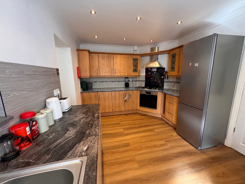 Modern kitchen with wooden cabinets, marble countertop, stainless steel appliances and wooden flooring