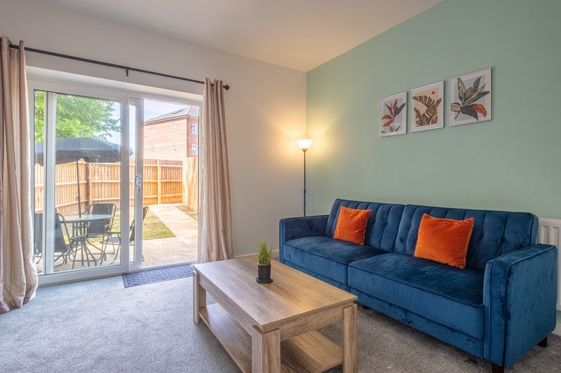 Bright living room with blue sofa, wooden coffee table, patio doors opening to garden