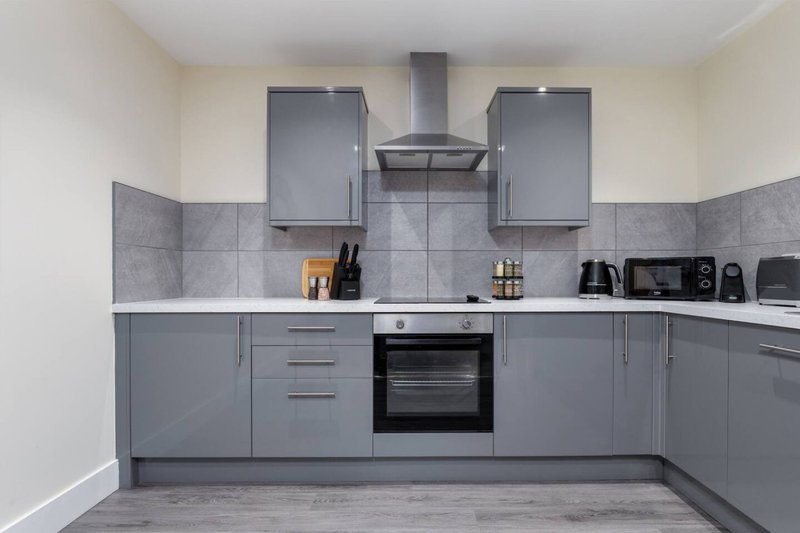 Modern kitchen with grey cabinetry, integrated oven, hob, and range hood