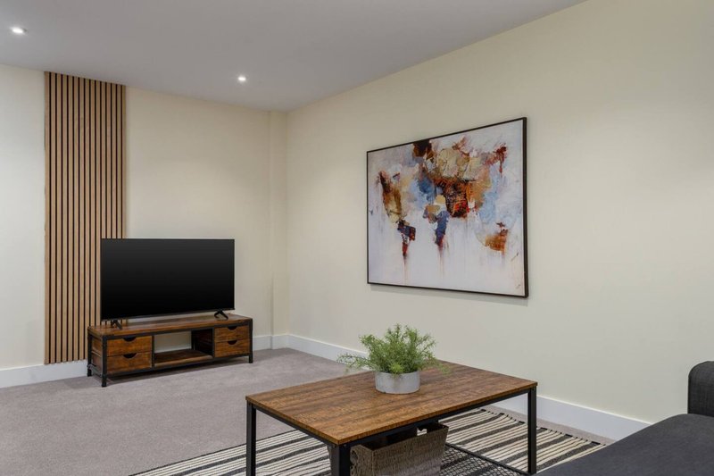 Modern living room with TV, wooden coffee table, world map artwork and potted plant