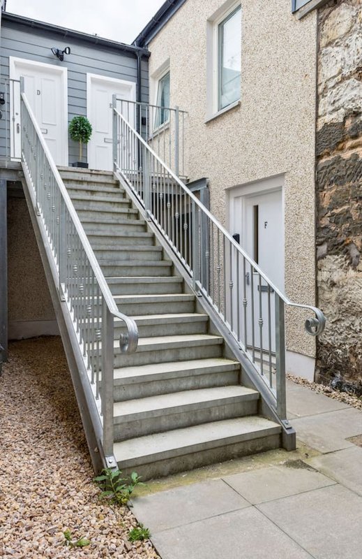 External staircase with metal handrail leading to residential entrance doors
