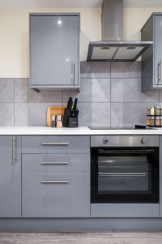 Modern kitchen with grey cabinetry, black oven, extractor hood and countertop appliances