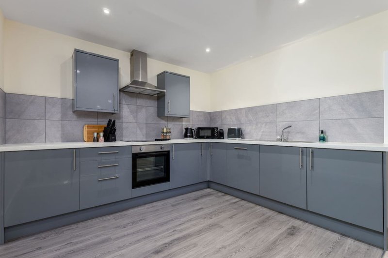 Modern kitchen with grey cabinetry, built-in appliances, tiled splashback and wooden flooring