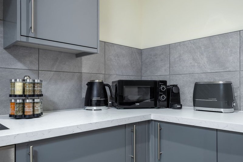 Modern kitchen corner with grey cabinetry, white countertop, and small appliances
