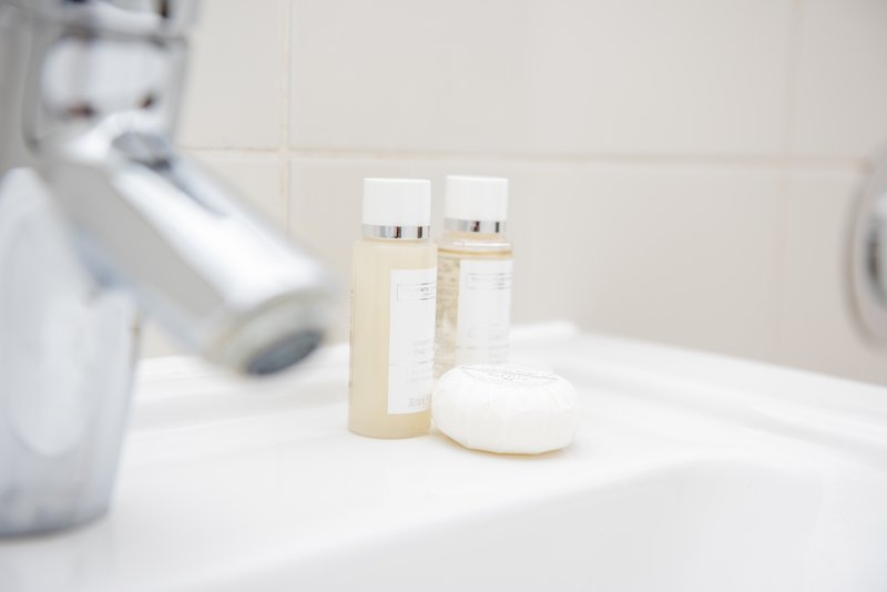 Bathroom counter with toiletries, soap dispenser, and bathroom fixtures