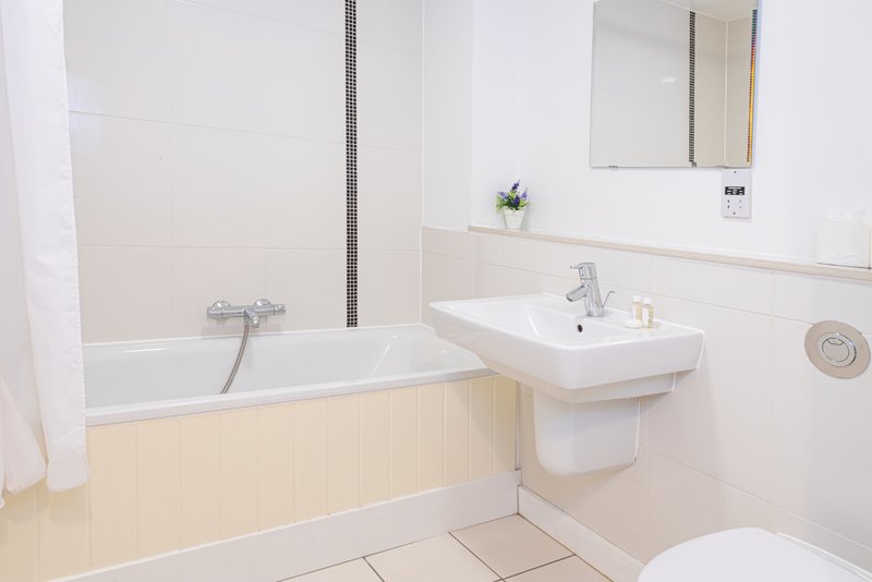 Modern bathroom with bathtub, wall-mounted sink, toilet, and mirror cabinet