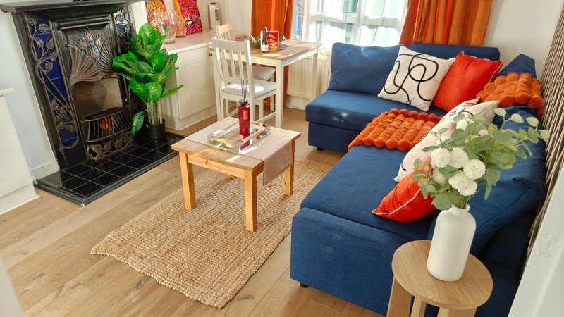 Modern living room with blue sectional sofa, wooden coffee table, fireplace and large windows with orange curtains