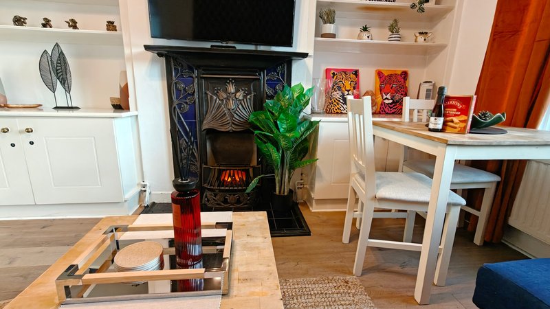 Living room with fireplace, TV, wooden dining table, white shelving and green plant
