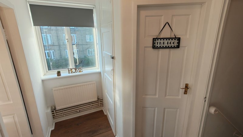 Hallway with white doors, radiator heater, window with blind, and wall hanging